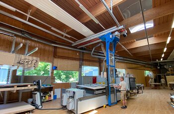 Arbeitsbereich mit CNC-Bearbeitungszentrum und Kragarmregal Ein GIS Kransystem mit Regalbediengerät sorgt dafür, dass die Holzplatten schnell und mühelos vom Kragarmregal auf den Arbeitstisch der Maschine gelangen
