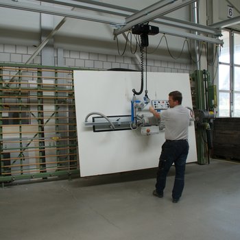Wooden panel is transported from the lift truck to the vertical saw with a vacuum handling system
