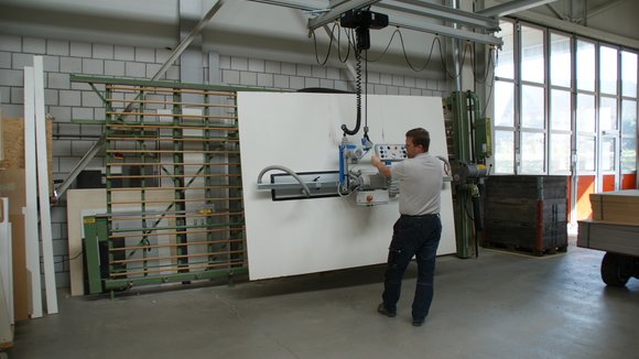 Holzplatte wird mit Vakuum-Handlingsystem vom Hubstapler zur Vertikalsäge transportiert