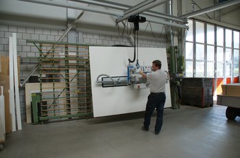 Wooden panel is transported from the lift truck to the vertical saw with a vacuum handling system